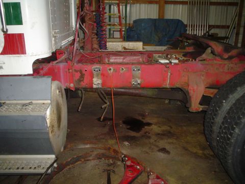 1966 International School Bus - The red frame of a truck is visible, with dual rear wheels and part of the cab on the left.