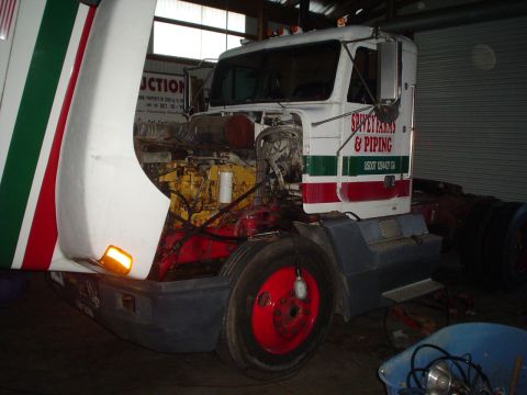 1966 International School Bus - A truck's engine is visible with its hood raised, red and green stripes on the cab.