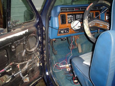 1984 Ford Bronco - Ford Bronco interior shows exposed door wiring and dashboard details. Aftermarket gauge is visible.