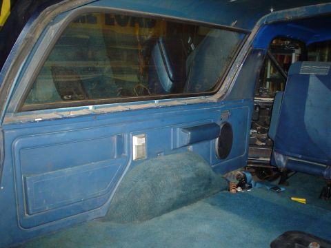 1984 Ford Bronco - The interior of a blue vehicle is shown, with a focus on the door panel and rear seating area.