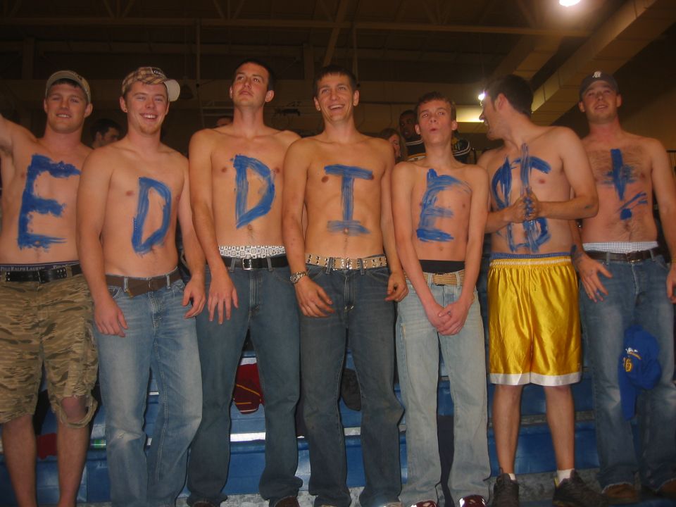 Group of young men with blue paint on their chests, some wearing jeans and shorts