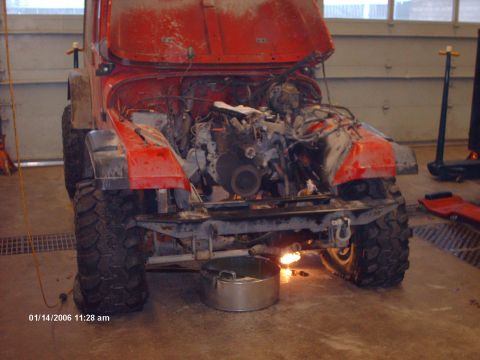 1988 Jeep Cherokee - A red Jeep is shown in a garage with its hood up and engine exposed, resting on large off-road tires.