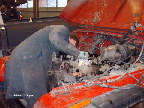 1988 Jeep Cherokee - Mechanic works on the engine of a 1988 Jeep Cherokee, with the hood open.
