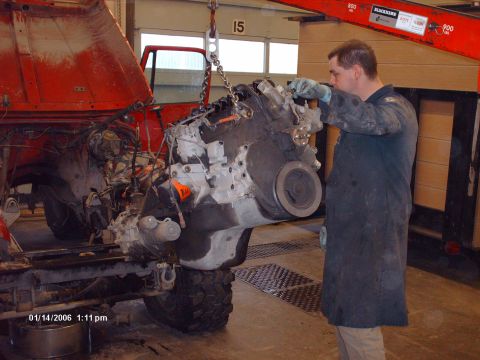 1988 Jeep Cherokee - Mechanic removes the engine from a red Jeep in a garage, with a hoist supporting the heavy component.