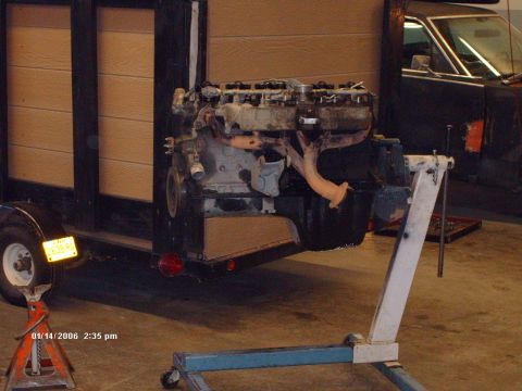 1988 Jeep Cherokee - An engine is mounted on a stand, with a trailer and a dark vehicle visible in the background.