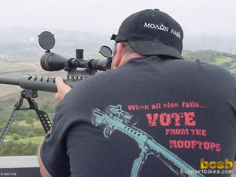 1989 Ford Bronco - Man aims a scoped rifle from a vantage point, wearing a hat and t-shirt with text and graphics.