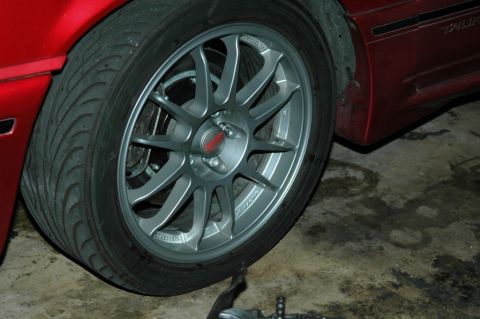 1991 Ford Taurus - Close-up of a silver multi-spoke wheel and tire on a red car.