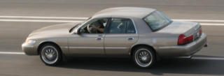 2001 Mercury Grand Marquis - A gold 2001 Mercury Grand Marquis is seen from the side while driving on a highway.