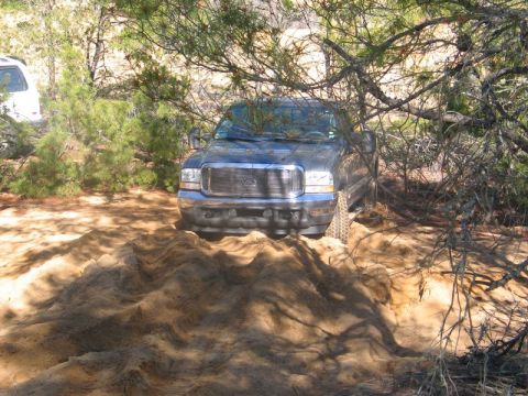 1995 Ford Bronco - A Ford F-Series truck navigates sandy terrain, with another vehicle partially visible behind it.