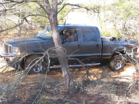 1995 Ford Bronco - Ford F-250 Super Duty navigating rough terrain with a driver in camouflage attire.