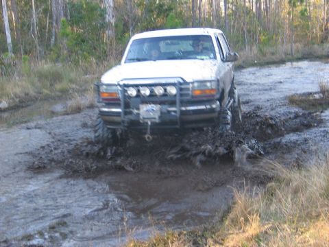 1995 Ford Bronco - 1995 Ford Bronco navigating a challenging muddy off-road course.