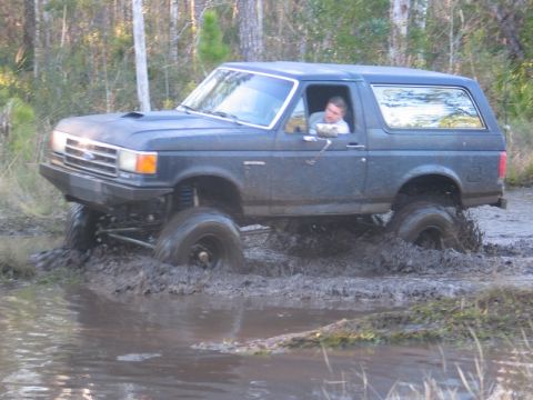 1995 Ford Bronco - A lifted 1995 Ford Bronco navigates through a muddy off-road course.