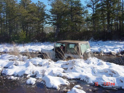 1995 Dodge 1500 - A Jeep Wrangler navigates through a snowy, watery terrain, with the driver visible inside the vehicle.