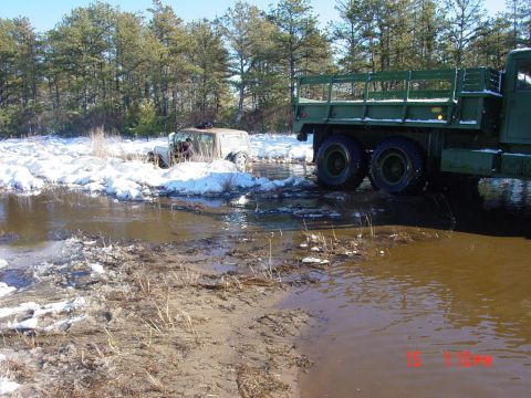 1995 Dodge 1500 - A Jeep is stuck in a muddy, snowy area while a large military truck is partially submerged in the water.