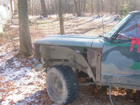 1984 Ford Bronco - This heavily modified Ford Bronco shows significant rust and damage to its front fender area.