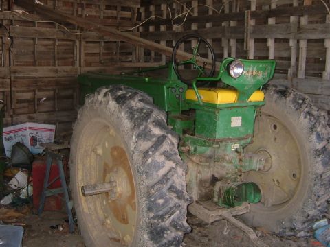 1984 Ford Bronco - A green tractor sits in a barn, its large rear tire dominating the foreground.
