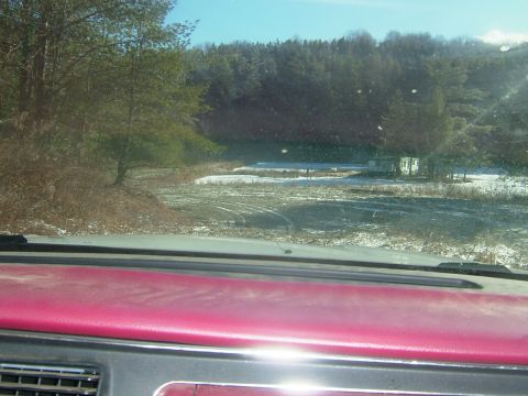1984 Ford Bronco - View from inside a vehicle shows a rural landscape with patches of snow and trees under a clear blue sky.