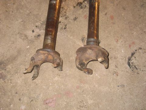 1995 Ford Bronco - Two heavily rusted CV joint assemblies are shown resting on a concrete surface.