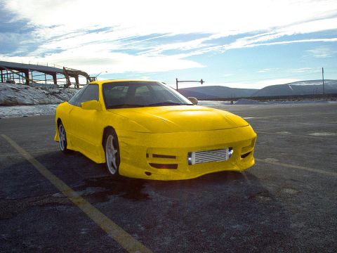 1994 Ford Probe - Yellow 1994 Ford Probe with aftermarket body kit and intercooler parked outdoors.