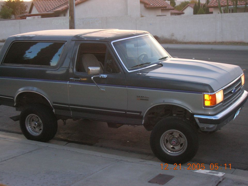 Two-tone gray lifted two-door SUV parked at curb, front 3/4 view, chrome wheels and bumper.
