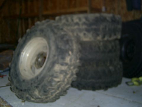 1977 Ford F-150 - Several off-road tires are stacked together, appearing dirty and used.