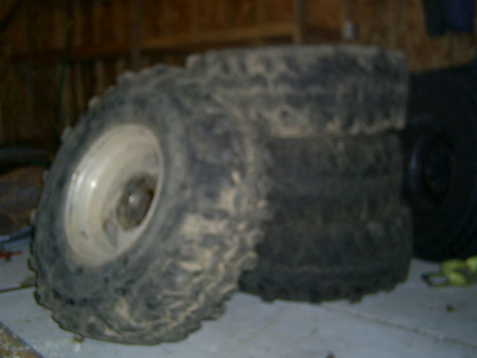 Stack of muddy off-road tires with white rims