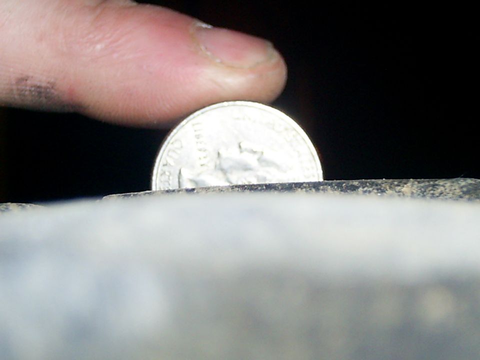 finger holding a quarter coin over a textured surface