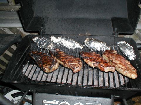 1979 Ford Bronco - Steaks and potatoes are grilled outdoors on a Char-Broil grill.