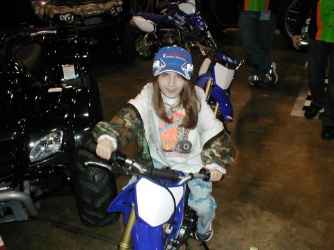 1979 Ford Bronco - Child poses on a dirt bike at an indoor event with other vehicles around.