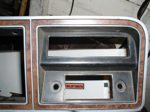 1979 Ford Bronco - Dashboard trim with wood grain accents and openings for a radio and gauges, likely from a 1979 Ford Bronco.