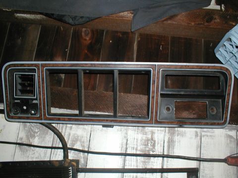 1979 Ford Bronco - This dashboard trim panel features wood grain accents and an air vent, likely from a vintage vehicle.