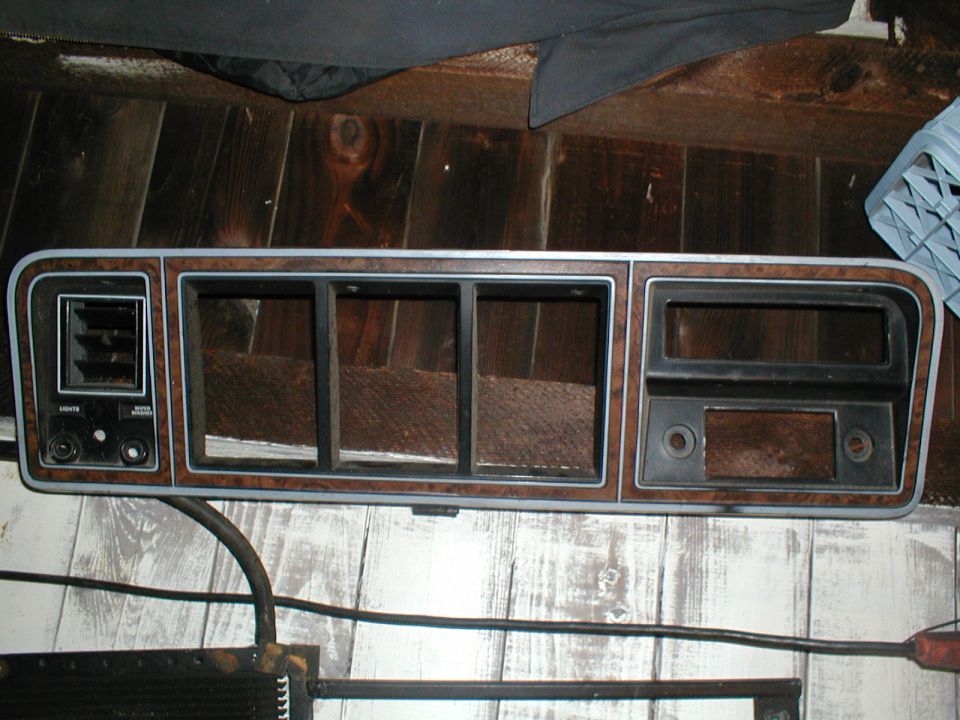 Dashboard trim panel with wood grain accents and air vent