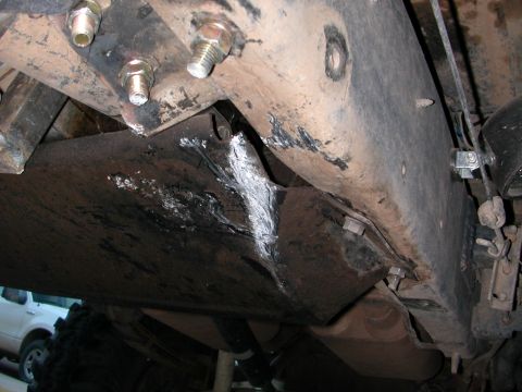 1984 Ford Bronco - Underside view of a vehicle's chassis, with a white SUV partially visible.