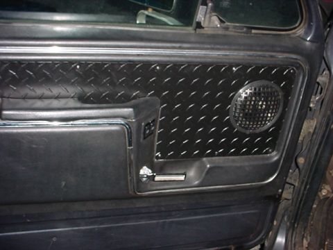 1983 Ford Bronco - The interior door panel features custom diamond plate accents and a circular speaker cover.