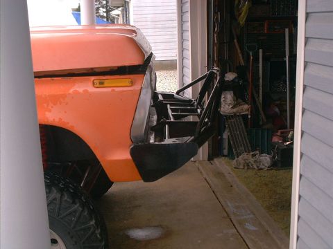 1978 Ford Bronco - The front corner of an orange 1978 Ford Bronco is visible, an aftermarket bumper and off-road tire.