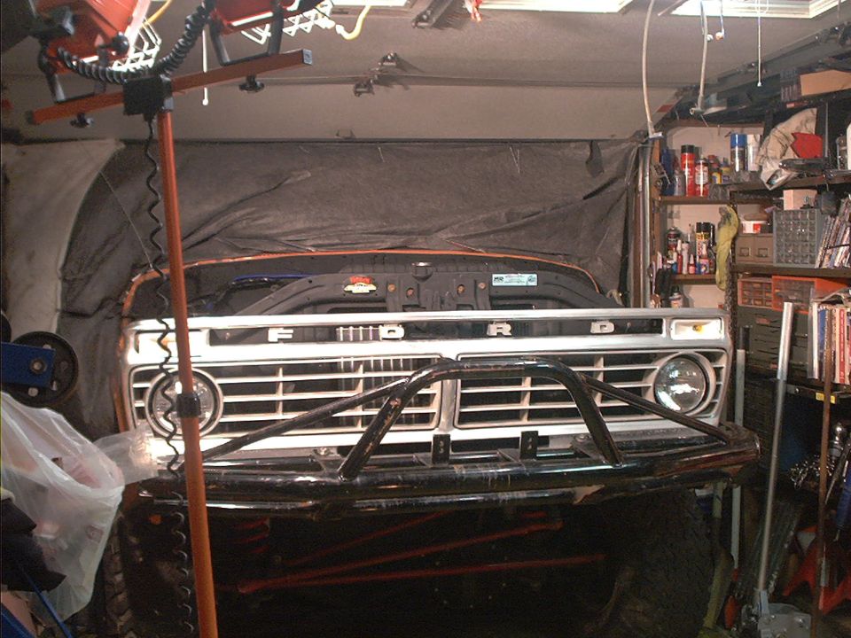 Front of a 1977 Ford truck with a custom bumper in a garage