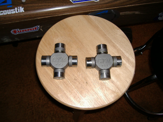 Two CTM U-joints on a wooden stool, with stickers on a wooden surface behind