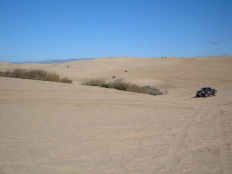 1985 Ford Ranger - Truck navigates sand dunes with other vehicles in the background.