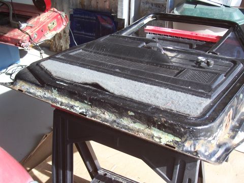 1978 Ford Bronco - A detached vehicle door panel is shown, revealing its internal structure and weathered exterior.