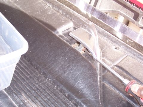 1978 Ford Bronco - A pry tool is used to remove a section of the interior door panel.