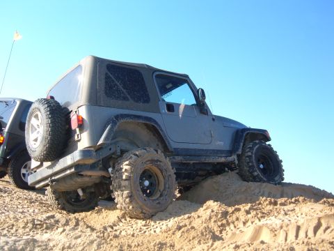 1985 Ford Ranger - Jeep Wrangler navigating a sandy terrain with a clear blue sky overhead.