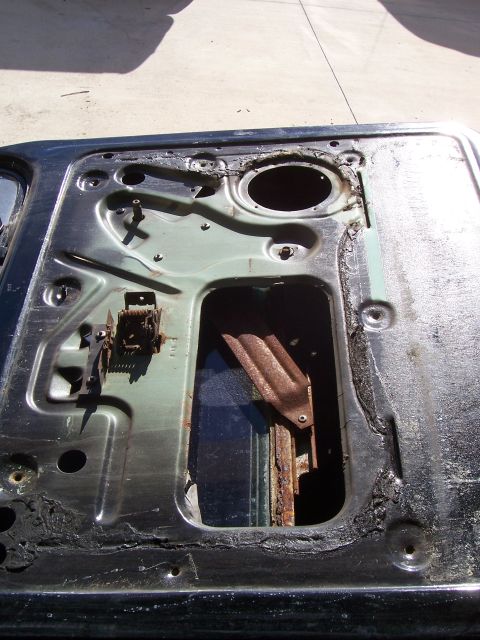1978 Ford Bronco - The inner workings of a car door, revealing the window regulator and signs of corrosion.