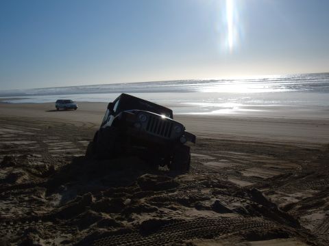 1985 Ford Ranger - Jeep stuck in sand on beach, another SUV visible in the background.