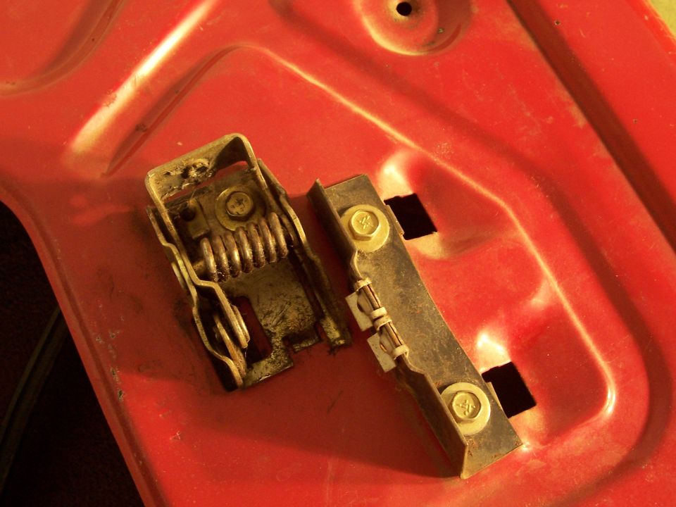 Door latch mechanism with spring and bolts on red surface. Supermotors.net logo visible
