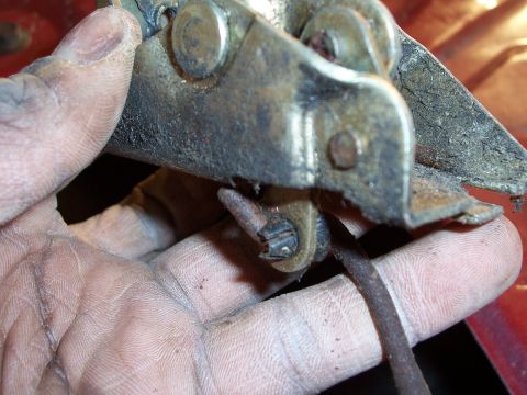 1978 Ford Bronco - A close-up view of a corroded door latch mechanism being held by a dirty hand.