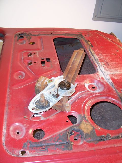 1978 Ford Bronco - Close-up of a car door's interior, revealing the window regulator and signs of wear and tear.