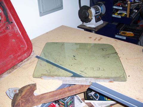 1978 Ford Bronco - Window glass and parts laid out on a workbench, possibly for a 1978 Ford Bronco.