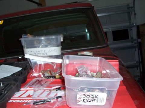 1978 Ford Bronco - Parts are organized in containers on the interior of a red vehicle, with labels indicating tailgate, topper, and right door components.