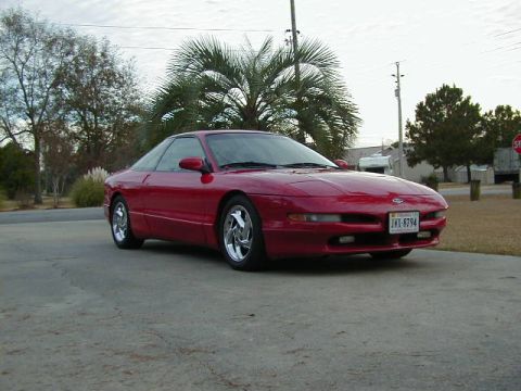1997 Ford Probe - A red coupe is parked on a concrete driveway with palm trees in the background.