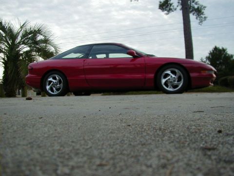 1997 Ford Probe - A red 1997 Ford Probe is shown from the side, parked outdoors under a cloudy sky.
